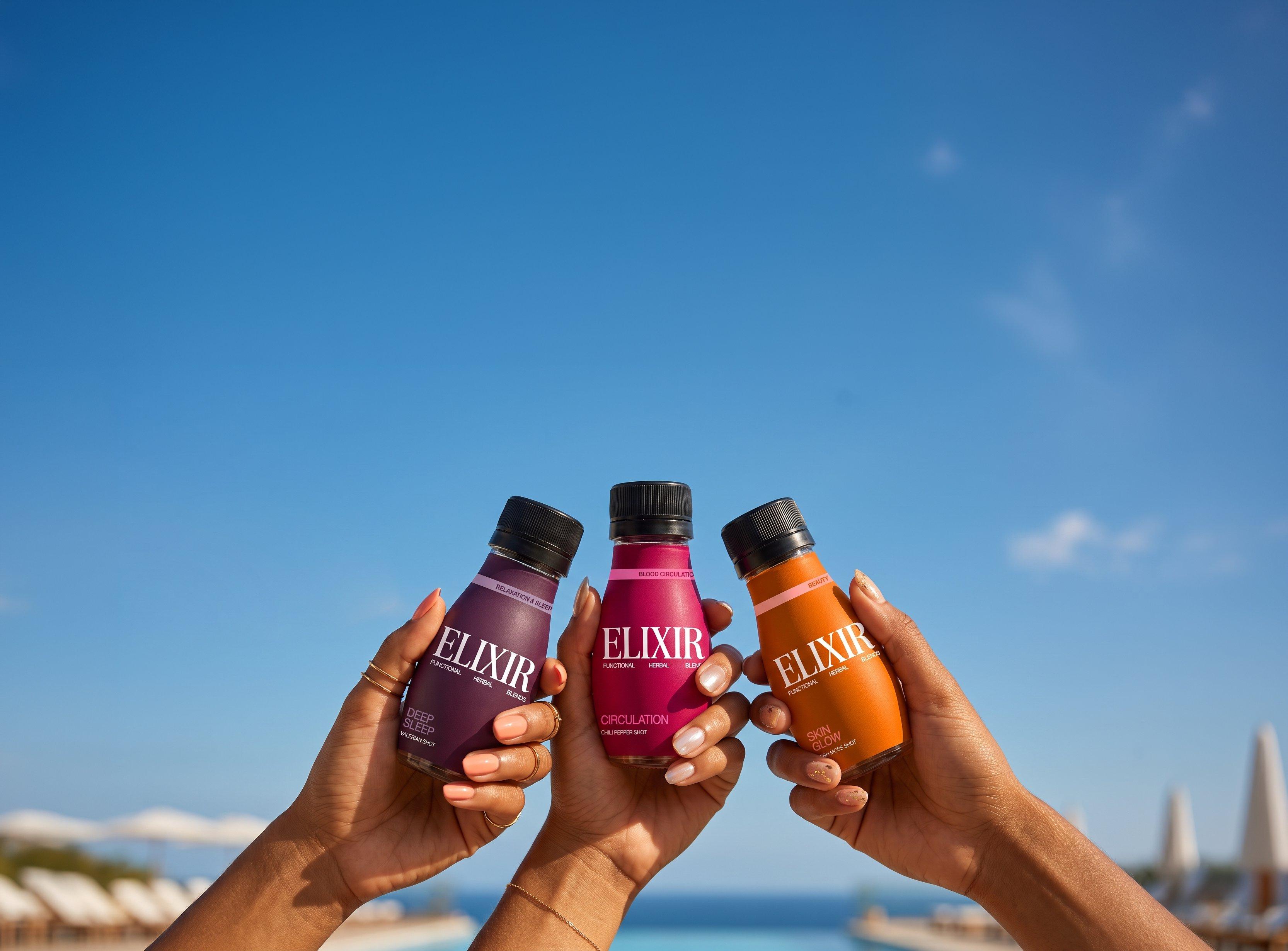 Three hands holding Elixir shots against a blue sky: Deep Sleep, Circulation and Skin Glow